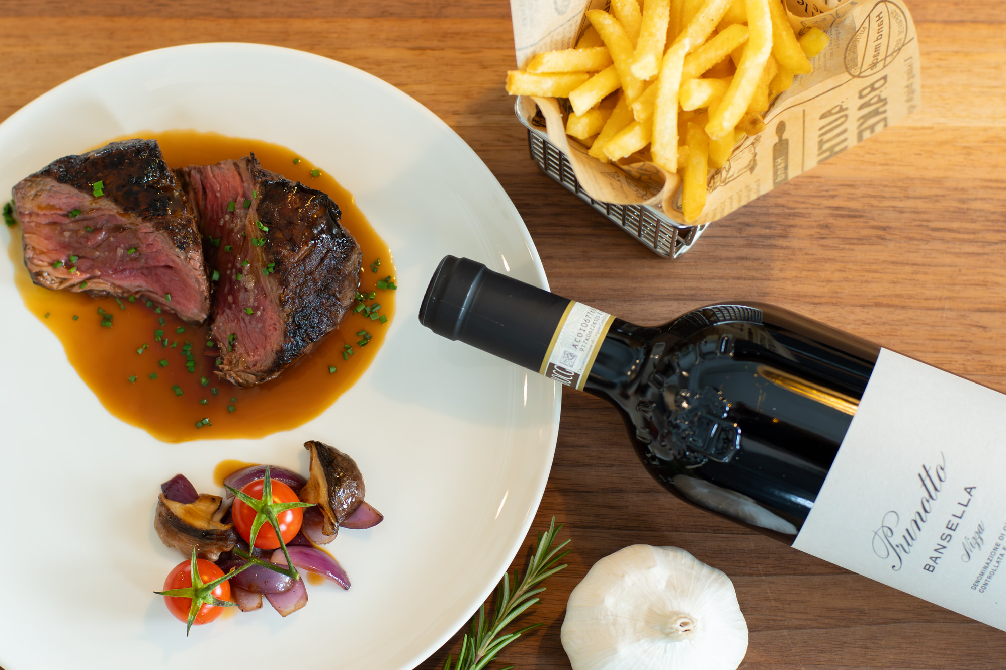 Teller mit Rindsentrecôte, schön garniert mit Pommes und Weinflasche, fotografiert vom Gastrofotograf Toggenburg & St. Gallen